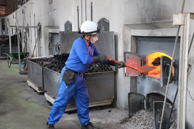 ポットスチルの釜に石炭をくべる作業